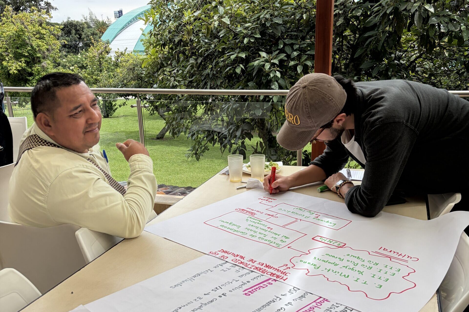 2 workshop participants discussing with working on a flipchart on which one is writing with markers