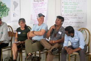 5 workshop participants discussing and one of them speaking on the microphone