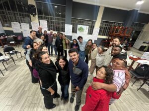 The whole group of workshop participants hugging and looking at the camera