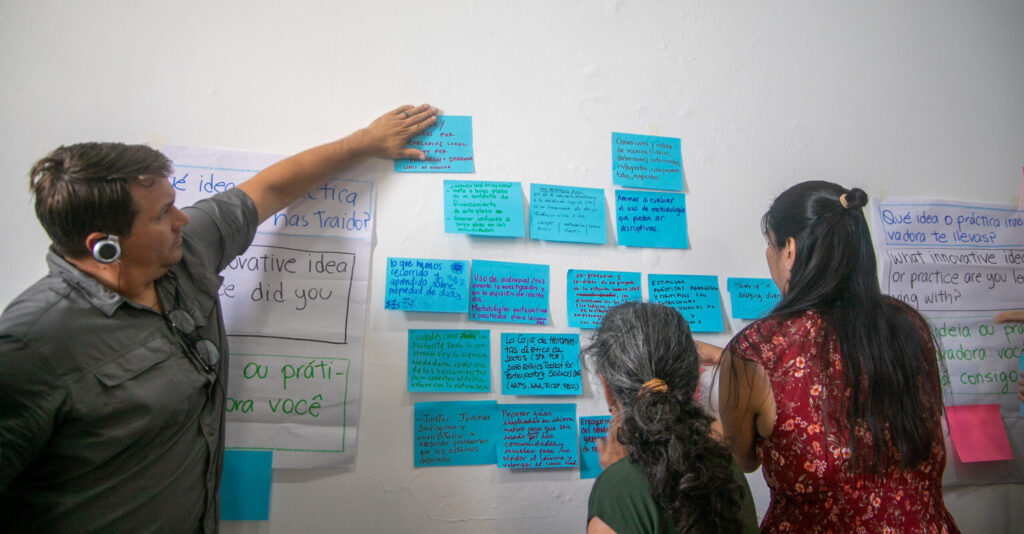 3 workshop participants discussing over pig post it notes on the wall